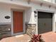 Inviting home entrance featuring a striking orange front door, stone accents and fresh landscaping at 5108 Rain Shadow Dr, St Cloud, FL 34772