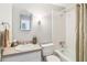 Bright bathroom featuring a single sink vanity, octagonal mirror and a tub with shower at 5413 Hansel Ave # K10, Orlando, FL 32809
