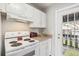 Functional kitchen with a white electric range, cabinets, and a doorway leading to the outdoor balcony at 5413 Hansel Ave # K10, Orlando, FL 32809