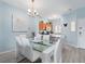 Open-concept dining room with a glass table, white chairs and modern chandelier at 136 Pompano Beach Dr, Kissimmee, FL 34746