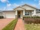 Tan house with a brick walkway, two-car garage and landscaping at 2514 Park Ridge St, Apopka, FL 32712