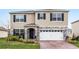 Charming two-story home features stone accents, blue shutters, attached garage, and well-maintained landscaping at 33425 Country House Dr, Sorrento, FL 32776