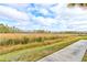 View of grassy landscape with a paved walkway and trees at 421 High Tide Ln, Daytona Beach, FL 32124