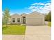 Tan house with two-car garage, landscaping, and a driveway at 6113 Chorus Dr, Mascotte, FL 34753