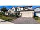 Two-story house with beige siding, solar panels, and a brick driveway at 7613 Wandering Way, Orlando, FL 32836
