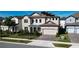 Two-story house with beige siding, solar panels, and a brick driveway at 7613 Wandering Way, Orlando, FL 32836