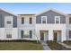 Two-story townhome with gray siding, dark brown doors, and a landscaped front yard at 1366 Lava Tree Dr, Davenport, FL 33897