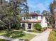 View of house featuring a tile roof, well-manicured lawn, mature trees, and a paved driveway leading to the garage at 141 Oakwood Way, Winter Park, FL 32789