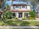 Charming two-story home featuring a tile roof, a pergola over the garage, and a lush landscaped yard at 141 Oakwood Way, Winter Park, FL 32789