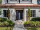 Close up of home's entry featuring a blue double door, manicured bushes, walkway, and exterior accent lighting at 141 Oakwood Way, Winter Park, FL 32789