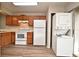 Efficient kitchen with wood cabinets, white appliances and stacked washer/dryer at 144 Reserve Cir # 112, Oviedo, FL 32765