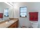 Well-lit bathroom with a single sink vanity, decorative mirror, and frosted window at 2048 Gloria Oak Ct, Orlando, FL 32820