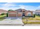 Tan two-car garage home with landscaping at 245 Viola Dr, Auburndale, FL 33823