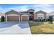 Two-car garage, light brown exterior, and well-manicured lawn at 245 Viola Dr, Auburndale, FL 33823