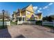 Inviting yellow townhomes with white picket fences and a communal brick courtyard with a bench at 2622 Lodi Cir # 103, Kissimmee, FL 34746