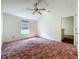 This bedroom features a large window, plush carpeting and a ceiling fan for a cozy atmosphere and natural light at 511 Coventry Ct, Mount Dora, FL 32757