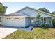 Inviting single-story home featuring light blue siding, a well-kept lawn, and an attached garage at 511 Coventry Ct, Mount Dora, FL 32757