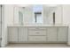 Bathroom featuring dual sinks, white cabinets, tiled floors, and a window at 5680 Brosnan Rd, St Cloud, FL 34771