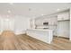Bright kitchen featuring white cabinets, quartz countertops, island and wood-look flooring at 5680 Brosnan Rd, St Cloud, FL 34771