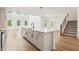 Open kitchen with stainless steel appliances, island with sink, white cabinets and wood floors at 5680 Brosnan Rd, St Cloud, FL 34771