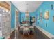 Bright blue dining room with a glass-top table, chandelier, and eclectic decor at 817 Antonette Ave, Winter Park, FL 32789