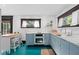 Modern kitchen features stainless steel appliances and teal painted floor at 817 Antonette Ave, Winter Park, FL 32789