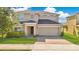 Charming two-story home with a well-manicured lawn, a paved driveway, and a two-car garage at 445 Kestrel Dr, Groveland, FL 34736