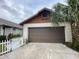 Attached brown garage featuring classic paneled door beneath a gabled roof and mature palm tree at 1138 Easton St, Orlando, FL 32825