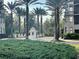 A secure gated entrance featuring a guardhouse surrounded by lush landscaping and towering palm trees at 14501 Grove Resort Ave # 1407, Winter Garden, FL 34787