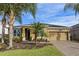 Tan one-story house with two-car garage, landscaping, and palm trees at 2158 Stillwood Way, St Cloud, FL 34771