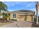 Tan one-story house with two-car garage, landscaping, and palm trees at 2158 Stillwood Way, St Cloud, FL 34771