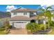 Charming two-story home with a well-manicured lawn, brick driveway, and lush landscaping with palm trees at 4455 Indigo Sky Ln, Kissimmee, FL 34744