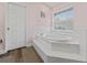 Bright bathroom with a large soaking tub, white tile, and natural light from the window at 657 Hunters Run Blvd, Lakeland, FL 33809