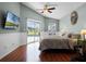 Main bedroom showing hardwood floors, ceiling fan, TV, and sliding glass doors to the screened-in pool area at 1101 Maidenmoor Rd, Winter Garden, FL 34787