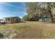 Wide shot of a lake house on a lawn under trees, next to a white building at 15040 Ne 248Th Avenue Rd, Fort Mc Coy, FL 32134