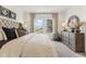 Bright bedroom featuring a tufted headboard, dresser with decor, and a view from the double windows at 1609 Hill Park Dr, Deltona, FL 32725