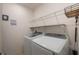 Well-lit laundry room features shelving and modern, front-load washer and dryer at 253 Golden Sands Cir, Davenport, FL 33837