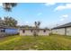 View of the backyard with grassy lawn, trees, and the rear exterior of the home at 451 Rogers St, Orlando, FL 32811