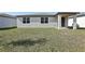 A wide shot of the grassy backyard featuring the exterior walls with windows and covered entryway at 4543 Sidesaddle Trl, St Cloud, FL 34772