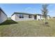 Grassy backyard with an exterior view of the home featuring windows, sliding doors, and a covered entryway at 4543 Sidesaddle Trl, St Cloud, FL 34772