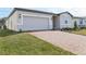 View of a single-story home featuring an attached garage, brick driveway, and manicured front yard at 4543 Sidesaddle Trl, St Cloud, FL 34772