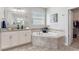 Elegant bathroom showcasing a corner tub, granite countertops, a large mirror, and ample natural light at 4608 Egg Harbor Dr, Kissimmee, FL 34746