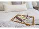 Close-up of a beautifully styled bed featuring soft pillows, a decorative tray with book, and a cozy blanket at 4608 Egg Harbor Dr, Kissimmee, FL 34746