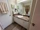 Bathroom vanity featuring a dark countertop, framed mirror, updated lighting, white cabinets and newer flooring at 482 Hildalgo Dr, The Villages, FL 32159