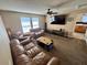 Comfortable living room with ample seating, large TV, ceiling fan, and natural lighting at 525 Aster Dr, Davenport, FL 33897