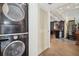Convenient laundry area with a stacked washer and dryer, located near a tiled hallway and stairs at 690 Osceola Ave # 604, Winter Park, FL 32789