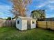 White shed with a gray door in a grassy backyard at 115 Cardamon Dr, Orlando, FL 32825