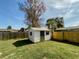 White shed with a gray door in a grassy backyard at 115 Cardamon Dr, Orlando, FL 32825
