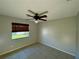 Well-lit bedroom with ceiling fan and window overlooking yard at 115 Cardamon Dr, Orlando, FL 32825