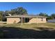 House exterior featuring a covered patio and a grassy backyard at 14476 Se 34Th Ct, Summerfield, FL 34491